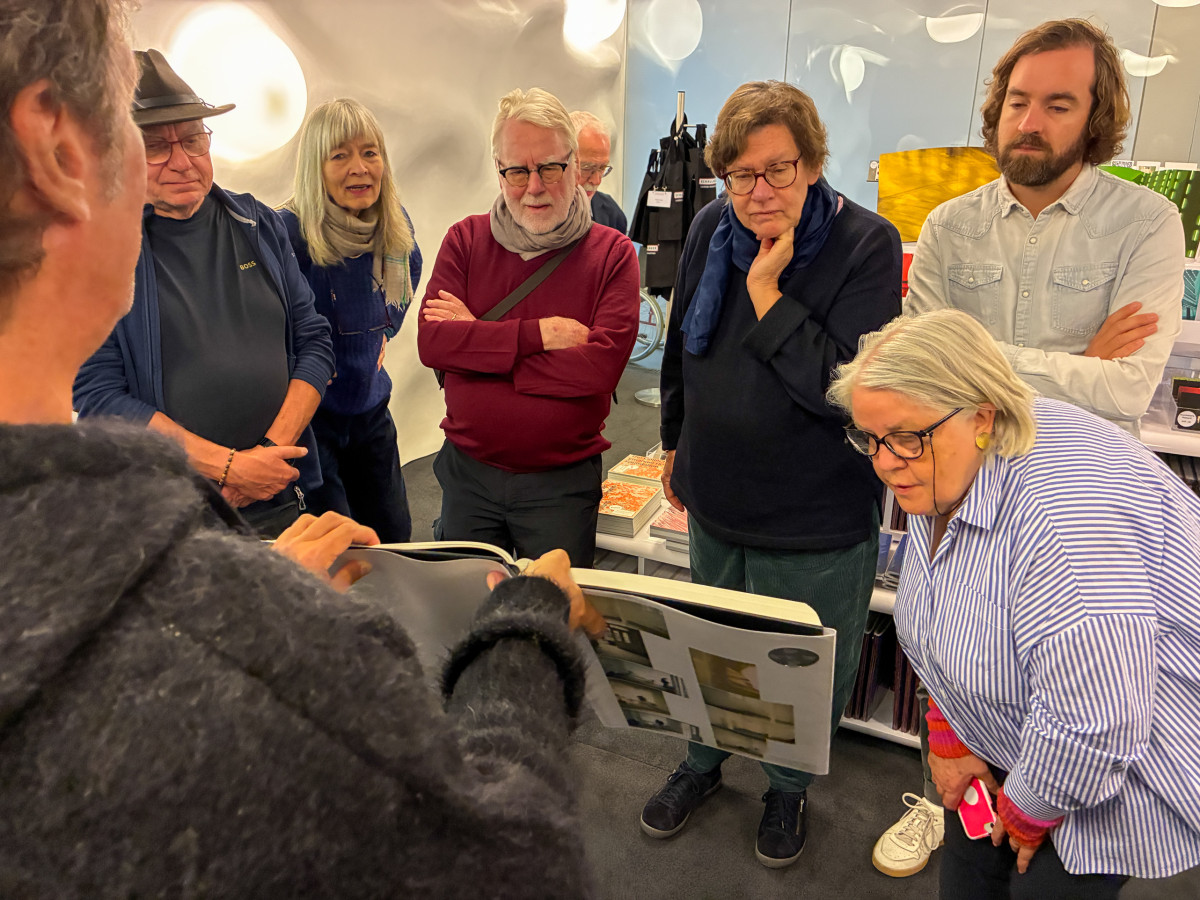 Gruppe betrachtet gemeinsam ein aufgeschlagenes Buch in einem hell erleuchteten Raum.