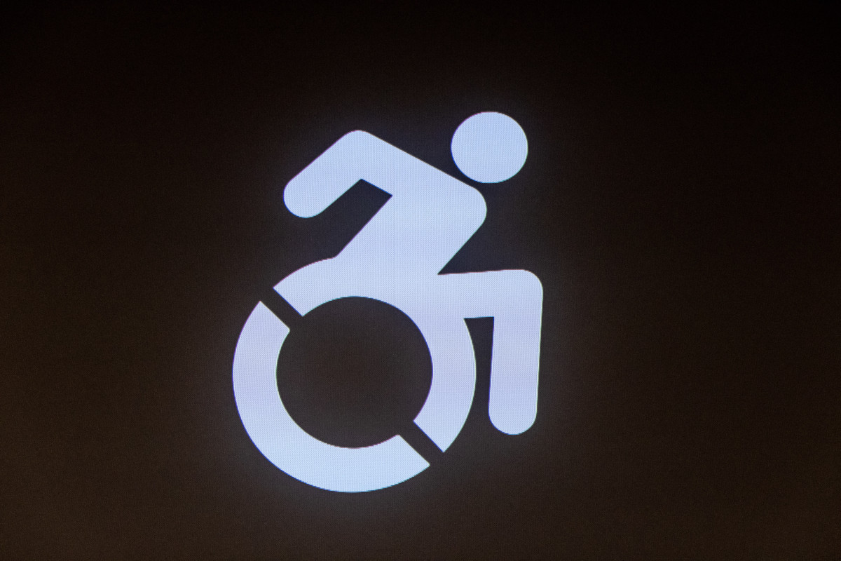 ein modernes Rollstuhl-Symbol, das den MEnschen nciht senkrecht, steif im Stuhl ruhend, sondern sich aktiv fortbewegend zeigt.